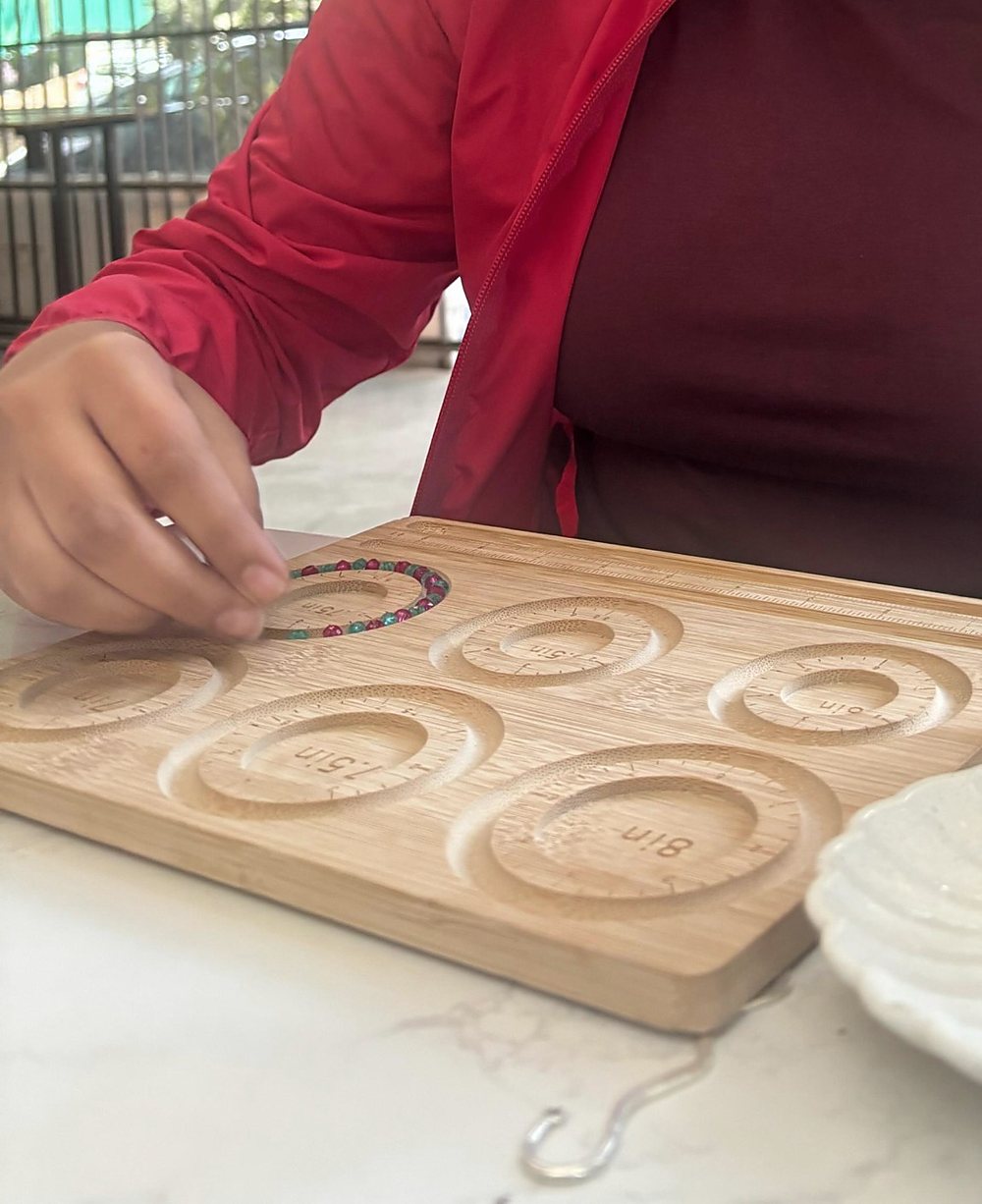 An Afterword bracelet being strung by hand